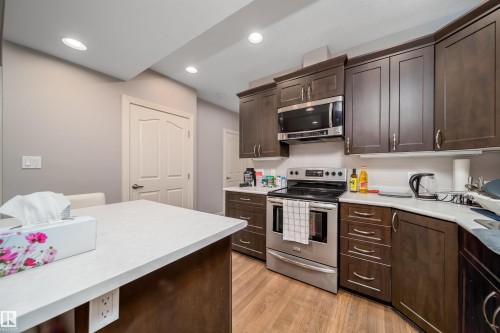 Kitchen featuring dark wood-finish cabinetry, stainless steel appliances, and wood-finish flooring - 11342 79 Avenue, Edmonton, AB - Indoor Photo Showing Kitchen