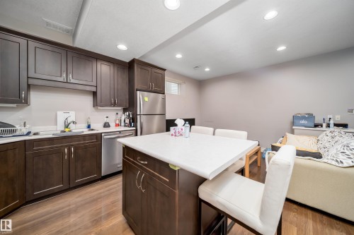 Kitchen area featuring dark wood-finish cabinetry, stainless steel appliances, a white countertop, and wood-finish flooring - 11342 79 Avenue, Edmonton, AB - Indoor Photo Showing Kitchen