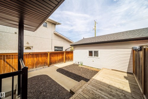 Rear property area featuring a wooden deck, concrete pathway, and decorative ground cover - 11342 79 Avenue, Edmonton, AB - Outdoor With Deck Patio Veranda With Exterior