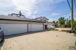 Detached two-car garage with white paneled doors and exterior wall lighting - 