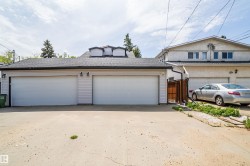 Detached garage structure featuring two overhead doors, light-colored siding, and a dark shingled roof with decorative dormers - 