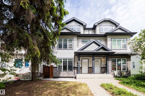 Duplex exterior featuring light gray siding, dark trim accents, and a stone facade - 11342 79 Avenue, Edmonton, AB - Outdoor With Facade