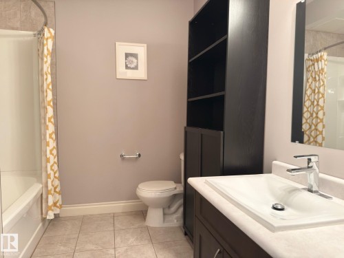 Tile flooring, modern vanity with integrated sink, chrome faucet, built-in shelving, and bathtub - 11342 79 Avenue Nw, Edmonton, AB - Indoor Photo Showing Bathroom