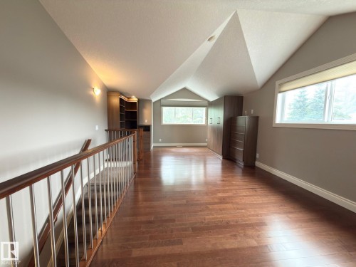 Vaulted ceiling, wood-finish flooring, built-in shelving, multiple windows, and a metal and wood-finish railing - 11342 79 Avenue Nw, Edmonton, AB - Indoor Photo Showing Other Room