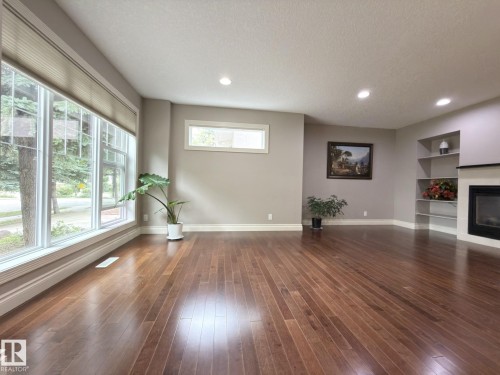 Hardwood flooring, recessed lighting, large bay windows, built-in shelving, and a fireplace with a mantel - 11342 79 Avenue Nw, Edmonton, AB - Indoor With Fireplace