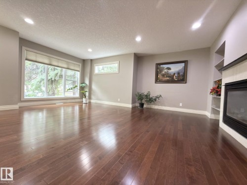 Spacious room featuring wood-finish flooring, recessed lighting, and a large window with roller shades - 11342 79 Avenue Nw, Edmonton, AB - Indoor With Fireplace