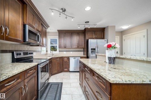 Kitchen featuring rich wood cabinetry, stainless steel appliances, light granite countertops, a tiled backsplash, and recessed lighting - 11342 79 Avenue, Edmonton, AB - Indoor Photo Showing Kitchen With Stainless Steel Kitchen With Upgraded Kitchen
