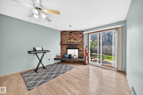 Living area featuring wood-finish flooring and a brick fireplace - 1928 68 Street Nw, Edmonton, AB - Indoor With Fireplace