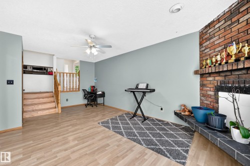 Living area featuring wood-finish flooring, a brick fireplace with a slate hearth, and a ceiling fan - 1928 68 Street Nw, Edmonton, AB - Indoor With Fireplace