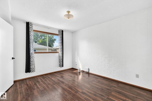 Room featuring wood-finish flooring, a double-paned window, and a flush-mount ceiling light fixture - 1928 68 Street Nw, Edmonton, AB - Indoor Photo Showing Other Room