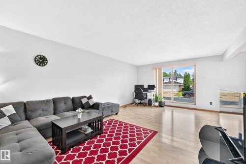 Spacious living area featuring light wood-finish flooring and ample natural light from a large picture window - 1928 68 Street Nw, Edmonton, AB - Indoor Photo Showing Living Room