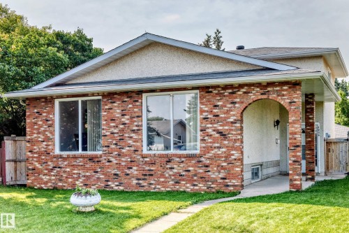 Brick and stucco exterior featuring an arched entryway and white framed windows - 1928 68 Street Nw, Edmonton, AB - Outdoor