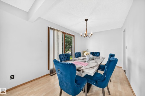 Dining area featuring light wood-finish flooring, a contemporary chandelier, and a sliding glass door providing natural light - 1928 68 Street Nw, Edmonton, AB - Indoor Photo Showing Dining Room