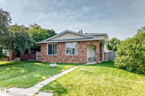 Brick-front exterior with an arched entryway, multiple windows, and a concrete pathway leading to the front door - 1928 68 Street Nw, Edmonton, AB - Outdoor