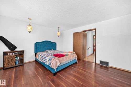 Spacious room featuring wood-finish flooring, white walls, and a textured ceiling - 1928 68 Street Nw, Edmonton, AB - Indoor Photo Showing Bedroom