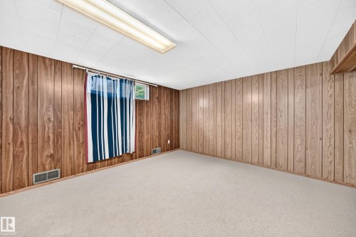 Carpeted room with wood-paneled walls and a white acoustic tile ceiling - 1928 68 Street Nw, Edmonton, AB - Indoor Photo Showing Other Room