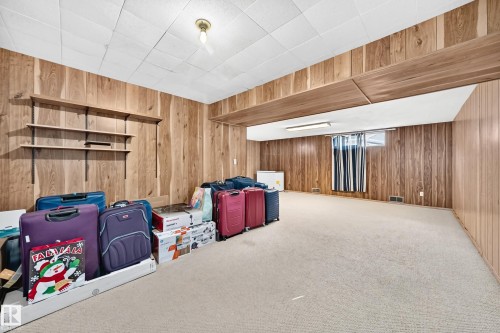 Spacious room featuring wood paneling, light-toned carpeting, and a drop ceiling - 1928 68 Street Nw, Edmonton, AB - Indoor