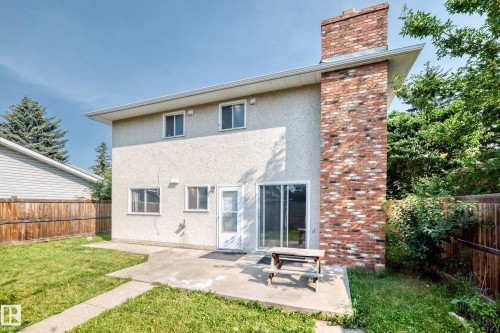 Expansive rear exterior featuring stucco siding and a prominent brick chimney - 1928 68 Street Nw, Edmonton, AB - Outdoor