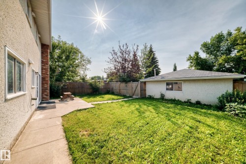 Spacious rear yard featuring an expansive lawn, concrete patio, and a detached structure with a shingled roof - 1928 68 Street Nw, Edmonton, AB - Outdoor