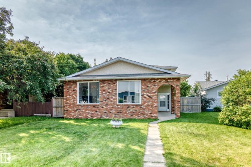 Brick exterior featuring an arched entryway, large front windows, and a concrete walkway - 1928 68 Street Nw, Edmonton, AB - Outdoor