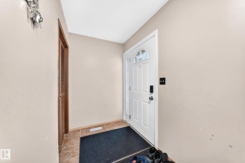 Entryway featuring a white paneled door with decorative glass, durable tile flooring, and a louvered closet door - 1928 68 Street Nw, Edmonton, AB - Indoor Photo Showing Other Room