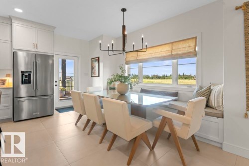 Dining area featuring a built-in window bench, large windows, and a contemporary chandelier - 2503 Lockhart Way, Cold Lake, AB - Indoor Photo Showing Dining Room