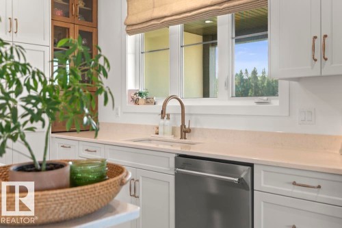 Kitchen featuring white shaker cabinetry, light-toned countertops, a stainless steel dishwasher, and a champagne bronze-finish pull-down faucet - 2503 Lockhart Way, Cold Lake, AB - Indoor Photo Showing Kitchen