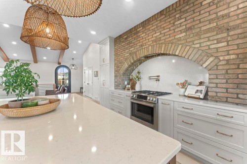 Kitchen featuring a stone archway, stainless steel range, white cabinetry with brushed nickel hardware, and light-toned countertops - 2503 Lockhart Way, Cold Lake, AB - Indoor Photo Showing Kitchen With Upgraded Kitchen