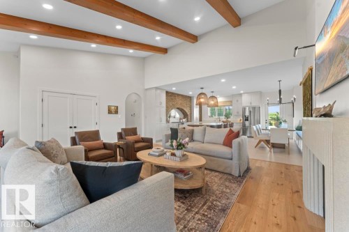 Spacious living area featuring high vaulted ceilings with exposed wood beams, light hardwood flooring, and a contemporary fireplace - 2503 Lockhart Way, Cold Lake, AB - Indoor