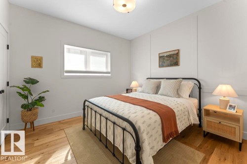 Bedroom featuring light wood-finish flooring, a contemporary ceiling light fixture, a wide window with white blinds, and white walls with vertical paneling details - 2503 Lockhart Way, Cold Lake, AB - Indoor Photo Showing Bedroom