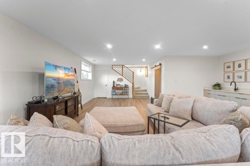 Spacious recreational area featuring recessed lighting, light wood-finish flooring, and a contemporary staircase with wood treads and metal balusters - 2503 Lockhart Way, Cold Lake, AB - Indoor Photo Showing Living Room