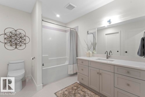 Bathroom featuring a light-toned vanity with dual sinks, a large mirror, and a full-size bathtub with an integrated shower - 2503 Lockhart Way, Cold Lake, AB - Indoor Photo Showing Bathroom