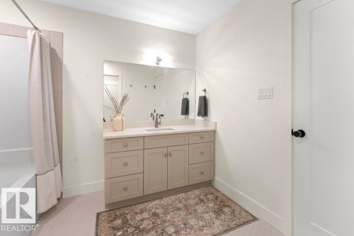 Bathroom featuring a single vanity with light-colored cabinetry, a light countertop, and a large wall-mounted mirror - 2503 Lockhart Way, Cold Lake, AB - Indoor Photo Showing Bathroom