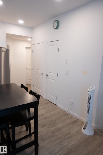 Recessed ceiling lighting illuminates a hallway with white paneled doors and wood-finish flooring - #103 860 Secord Bv Nw, Edmonton, AB - Indoor Photo Showing Other Room