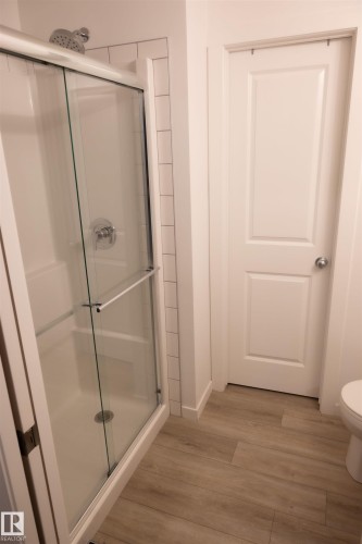 Walk-in shower with a glass enclosure, subway tile surround, and chrome fixtures - #103 860 Secord Bv Nw, Edmonton, AB - Indoor Photo Showing Bathroom