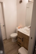 Modern bathroom vanity with wood-finish cabinetry, black hardware, and a white countertop with an integrated sink - 