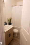 Bathroom featuring a light wood-finish vanity with a white countertop and integrated sink, complementing the wood-finish flooring - 