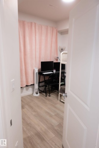 Room featuring wood-finish plank flooring and light-colored walls - #103 860 Secord Bv Nw, Edmonton, AB - Indoor