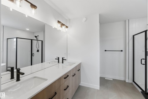 Double vanity with wood-finish cabinetry, white countertops, and matte black fixtures - 5872 Raven Crescent Nw, Edmonton, AB - Indoor Photo Showing Bathroom