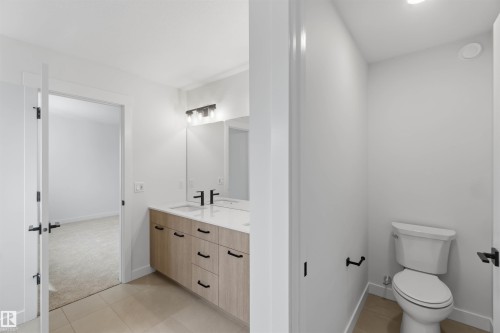 Bathroom featuring a double vanity with wood-finish cabinetry, white countertop, and matte black fixtures - 5872 Raven Crescent Nw, Edmonton, AB - Indoor Photo Showing Bathroom