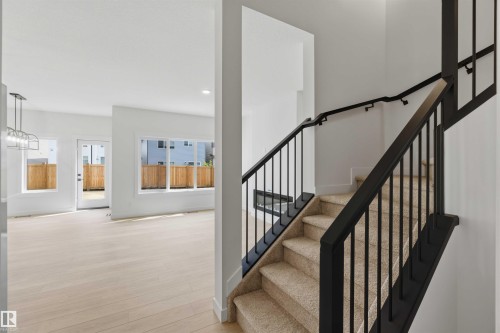 Carpeted staircase with black metal railings and handrails - 5872 Raven Crescent Nw, Edmonton, AB - Indoor Photo Showing Other Room