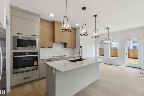 Modern kitchen featuring an expansive island with an undermount sink and black faucet - 5872 Raven Crescent Nw, Edmonton, AB - Indoor Photo Showing Kitchen With Upgraded Kitchen
