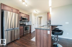 Kitchen featuring stainless steel appliances, dark wood-finish cabinetry, granite countertops, and wood-finish flooring - 