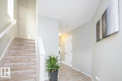 Carpeted staircase with white balusters and handrails, complemented by a light-colored window - 