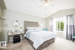 Vaulted ceiling bedroom featuring a ceiling fan with integrated lighting, broad window, and plush carpet flooring - 
