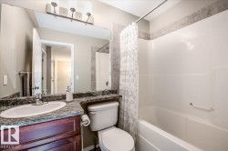 Bathroom featuring a white bathtub with an integrated shower, a vanity with a dark wood-finish cabinet, a granite-finish countertop, and an oval undermount sink - 