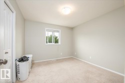 Carpeted room featuring light gray walls, a window with horizontal blinds, a white paneled door with a silver knob, and a ceiling-mounted light fixture - 