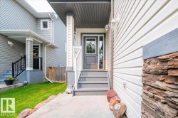 Exterior featuring stone accents, horizontal siding, and a covered porch with painted stairs - 