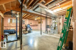 Unfinished basement featuring exposed wood joists, a concrete floor, visible HVAC ductwork, and insulation-lined walls - 