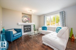 Living area featuring rich wood-finish flooring, a contemporary fireplace with a tiled surround and mantel, and a large sliding glass door - 